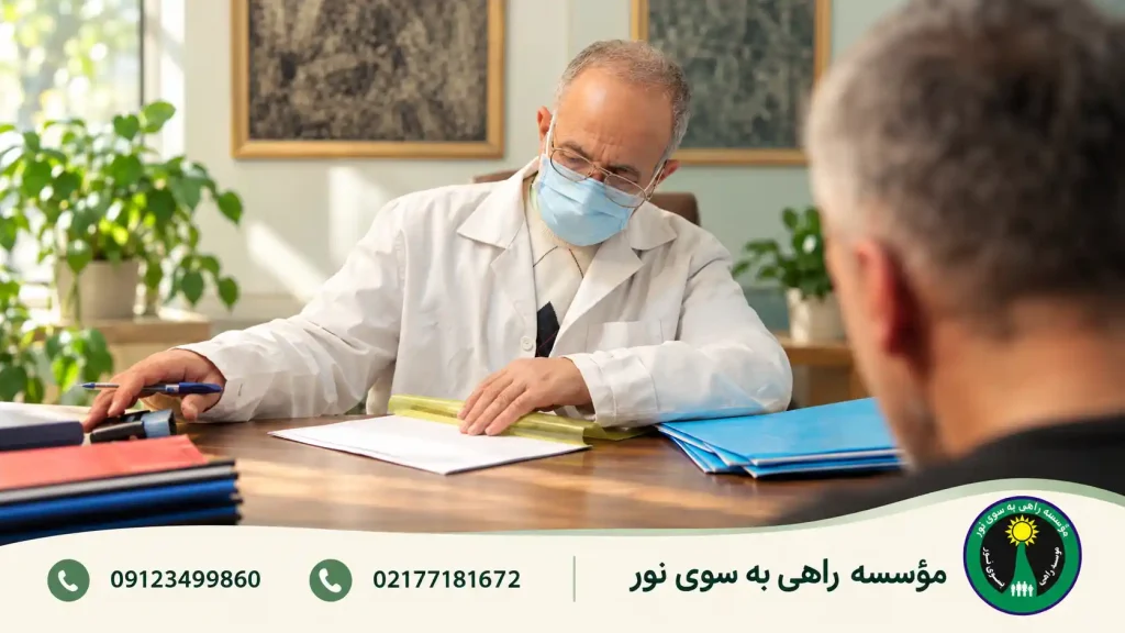 پزشک در حال بررسی پرونده در گفت‌وگو با مراجعه‌کننده پشت میز چوبی